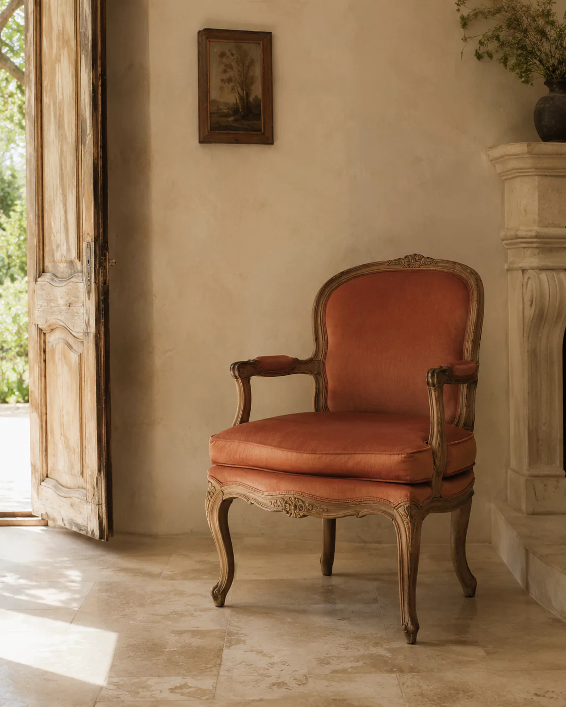 An antique terracotta armchair beside an open sunlit doorway.